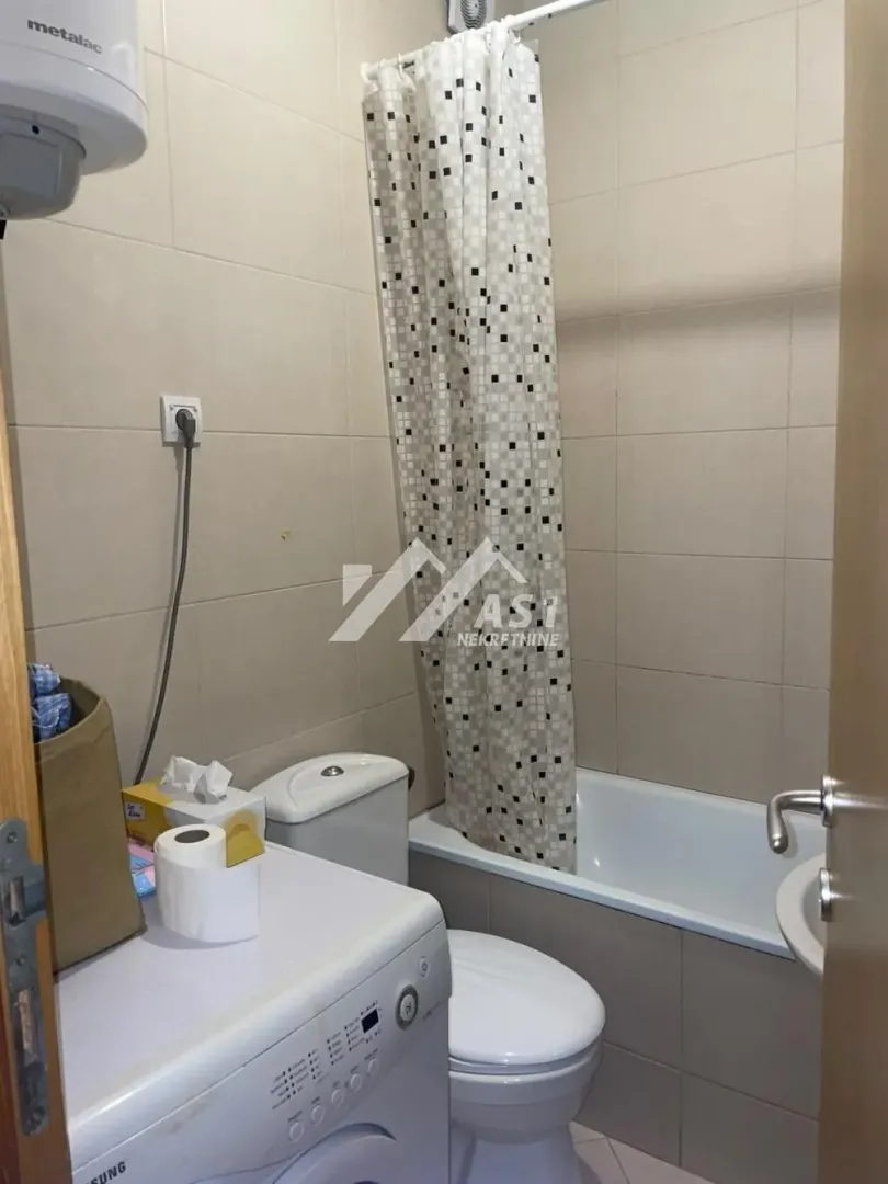 Manje kupatilo opremljeno kadom, wc šoljom, umivaonikom i veš mašinom.