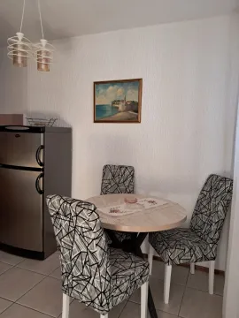 Dining area with a table, chairs, and a refrigerator. - image 7