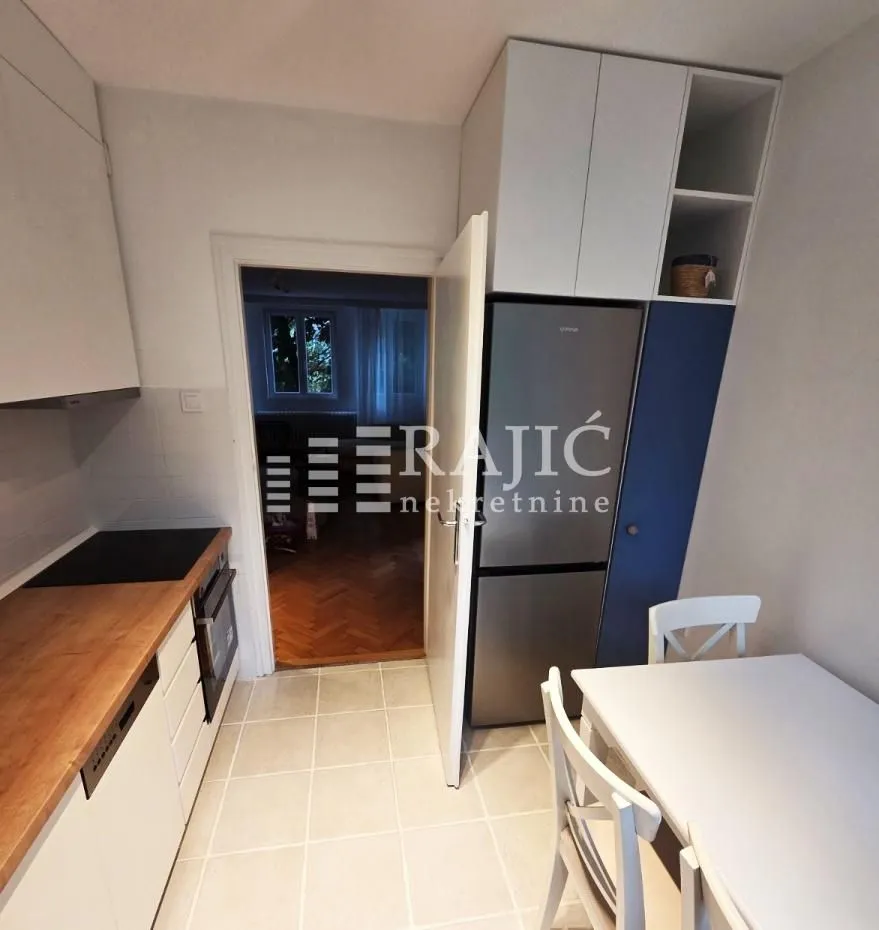 Smaller equipped kitchen with a dining table and refrigerator.