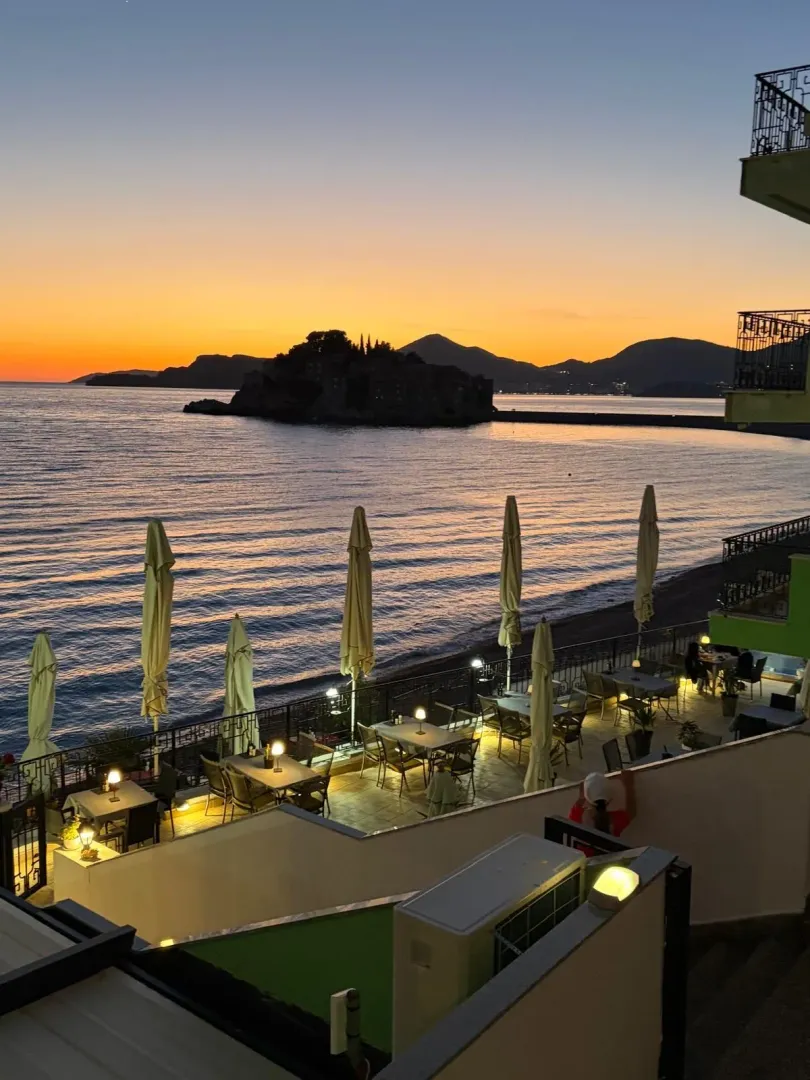 Pogled sa terase na more i Sveti Stefan tokom zalaska sunca.