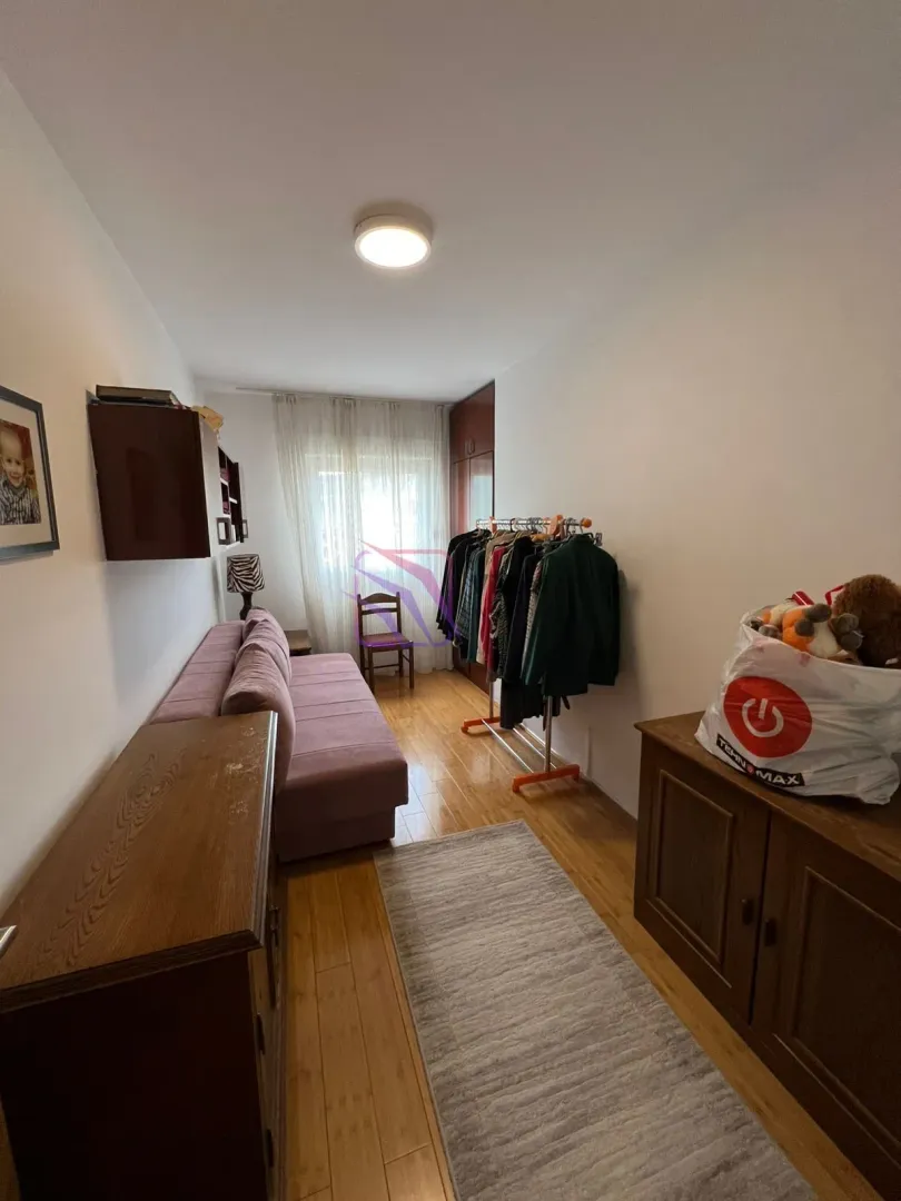Manja dnevna soba sa kaučem, drvenim komodama i stalkom za odjeću.