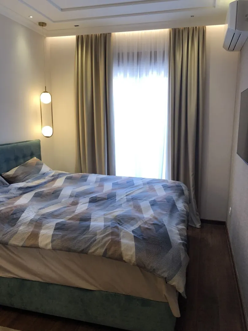 Bright bedroom with a large bed and modern lighting.