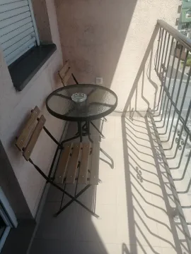 Small furnished balcony with a table and two chairs. - image 7