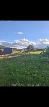 Pogled na zelenu livadu i okolne kuće u prirodi. - image 3