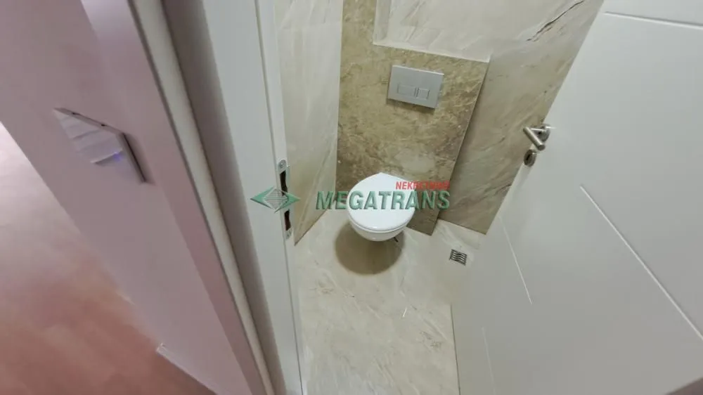 Pogled na manje kupatilo sa wc šoljom i keramičkim pločicama.