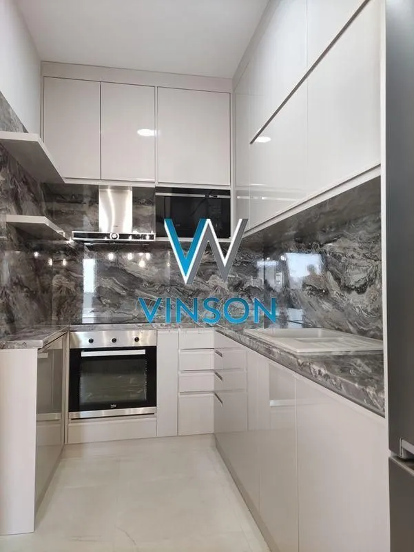 Modern U-shaped kitchen with built-in appliances and marble countertops.