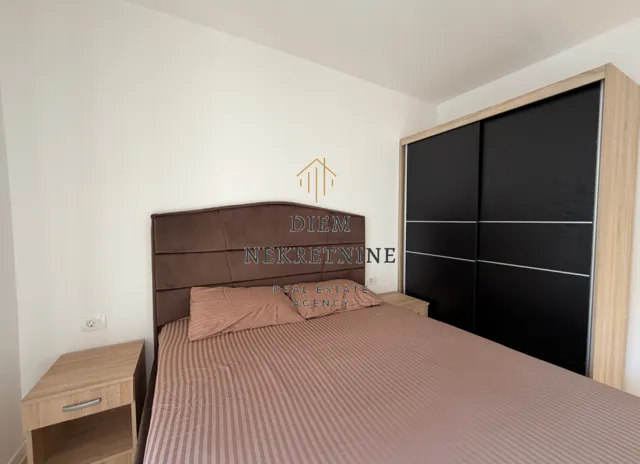 Furnished bedroom with a double bed and a wardrobe.
