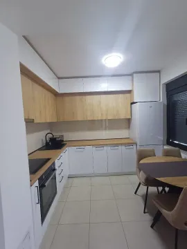 Modern kitchen with a dining table and white cabinets. - image 2