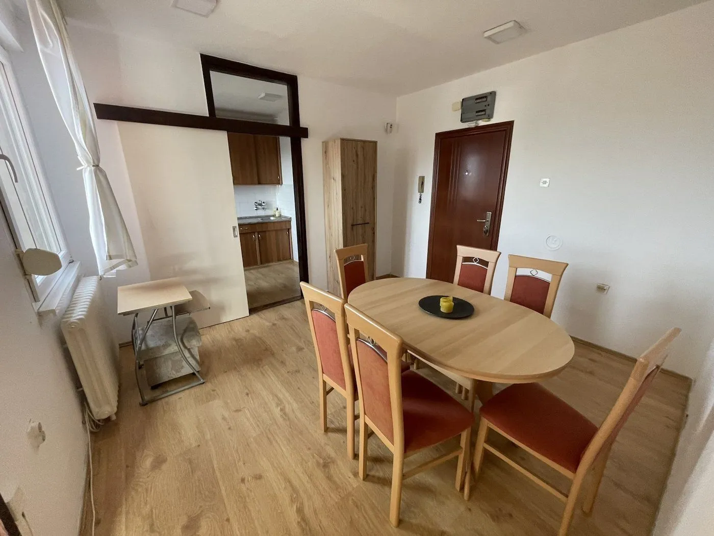 Dining area with a wooden table and chairs, looking into the kitchen.