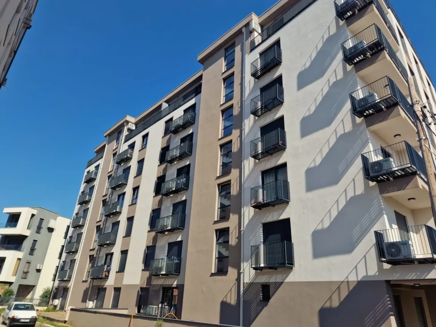 Spoljašnji izgled moderne višestambene zgrade sa terasama i balkonskim ogradama.