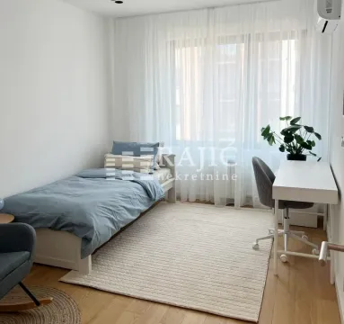 Bright bedroom with a bed, a desk, and a large window. - image 13