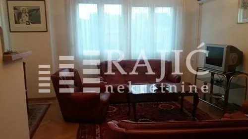 Dnevni boravak sa garniturom za sedenje i televizorom.