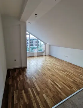 Prazna potkrovna prostorija sa parketom i kosim plafonom. - image 2