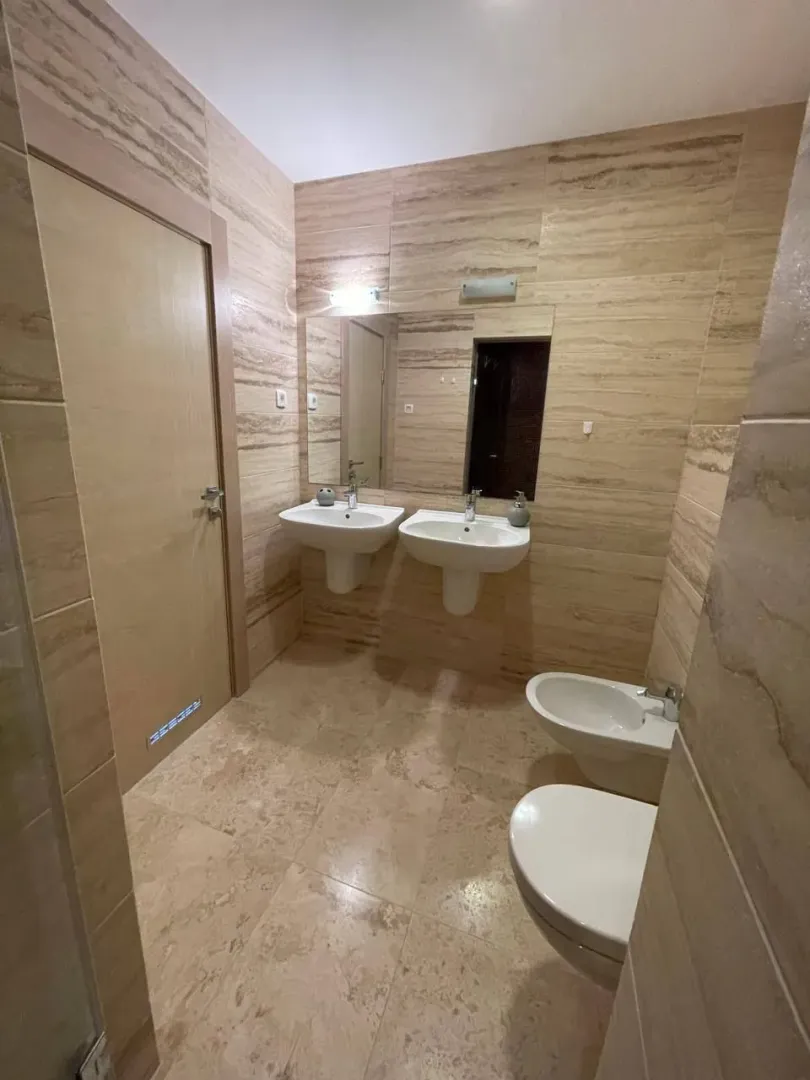 Moderne kupatilo obloženo keramičkim pločicama sa dva umivaonika, wc šoljom i bideom.