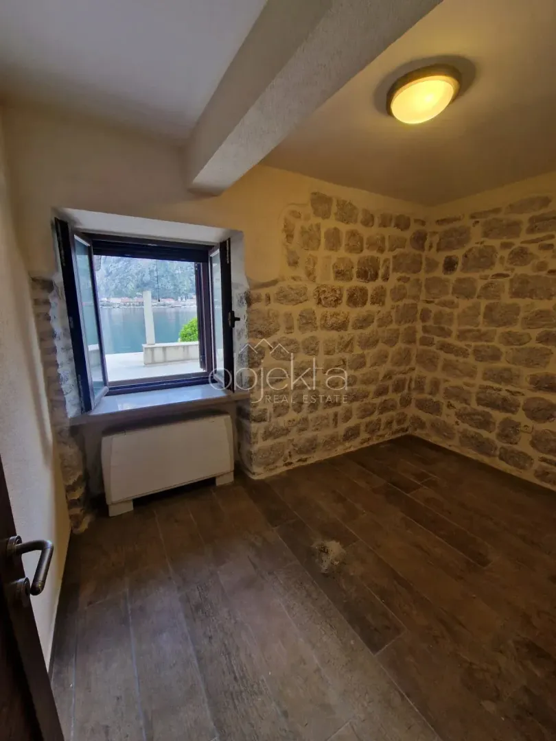 Empty room with a stone wall and a window with a sea view.