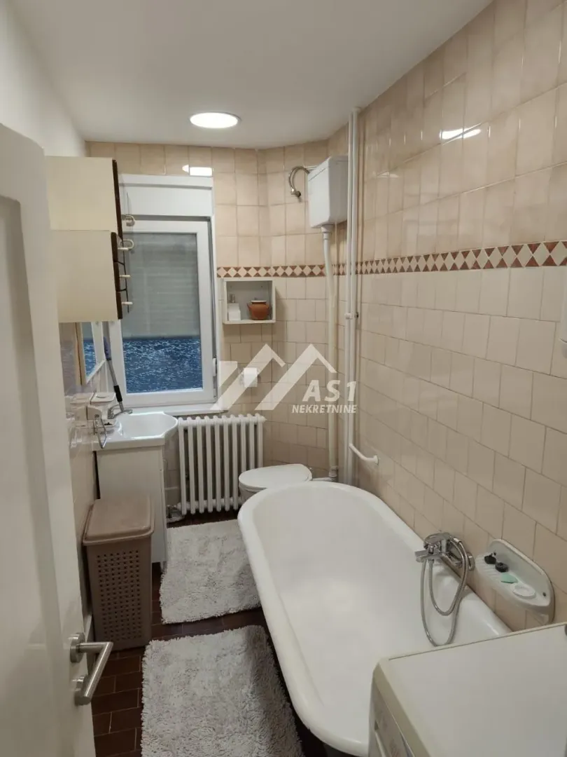 Manje kupatilo sa kadom, umivaonikom, wc šoljom i prozorom.