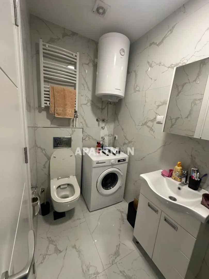 Manje kupatilo sa veš mašinom, WC šoljom, lavaboom i bojlerom.