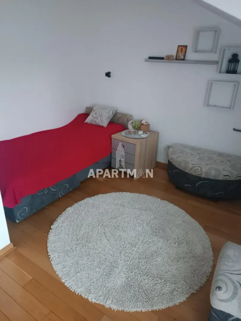 Small bedroom with a bed, bedside table, and a round rug.