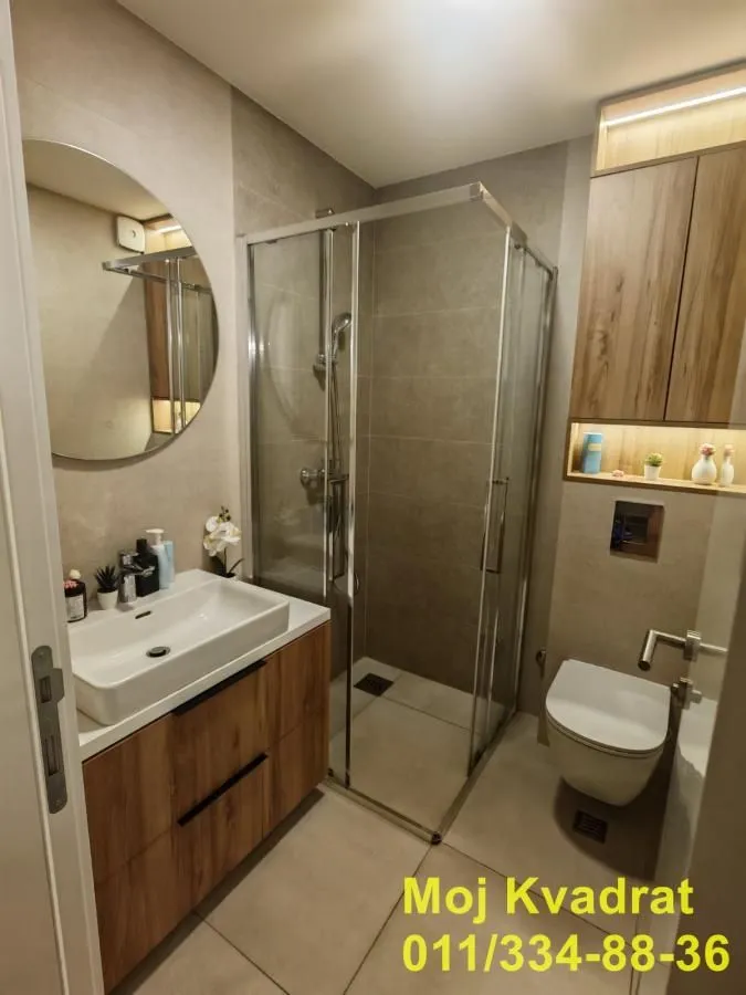 Savremeno opremljeno kupatilo sa tuš kabinom, umivaonikom i WC šoljom.
