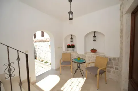 Covered terrace with a table, two chairs and stone walls. - image 9