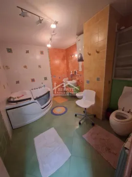 Spacious bathroom with a corner bathtub, shower, toilet, and sink. - image 8
