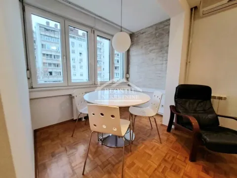 Trpezarija sa stolom, stolicama i velikim prozorima koji gledaju na okolne zgrade. - image 11