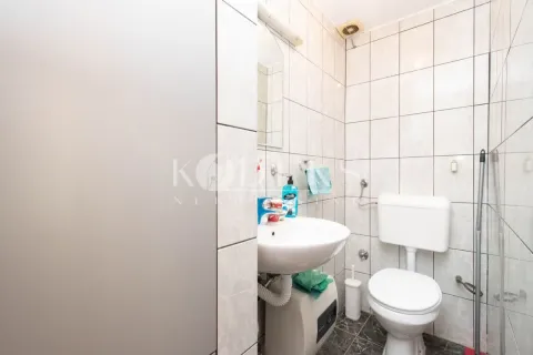 Small bathroom lined with ceramic tiles featuring a sink and a toilet. - image 4