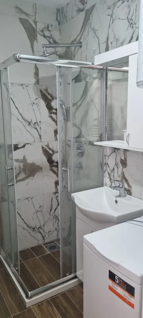 Moderno opremljeno kupatilo sa tuš kabinom i umivaonikom.