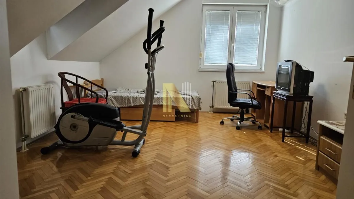 Potkrovlje sa krevetom, radnim stolom i spravom za vežbanje.