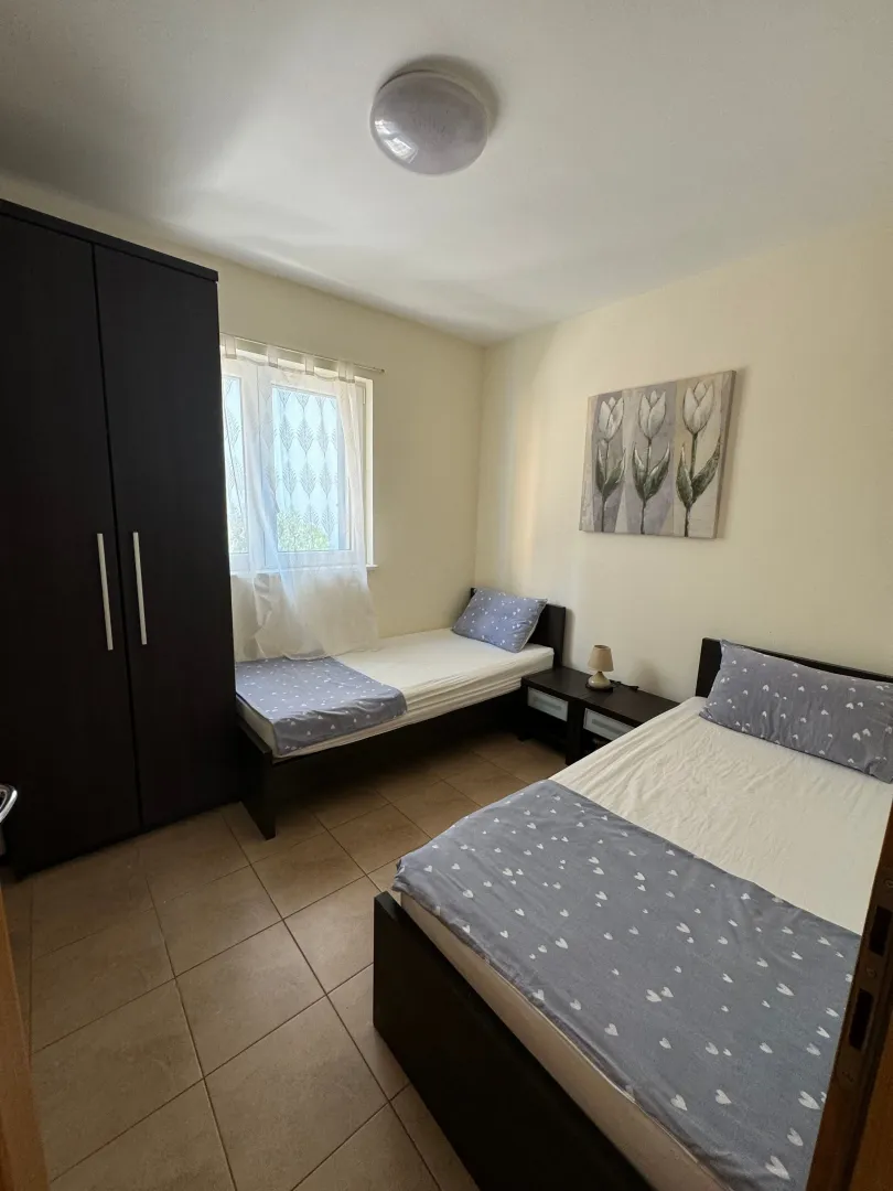 Namještena spavaća soba sa dva singl kreveta i ormarom.