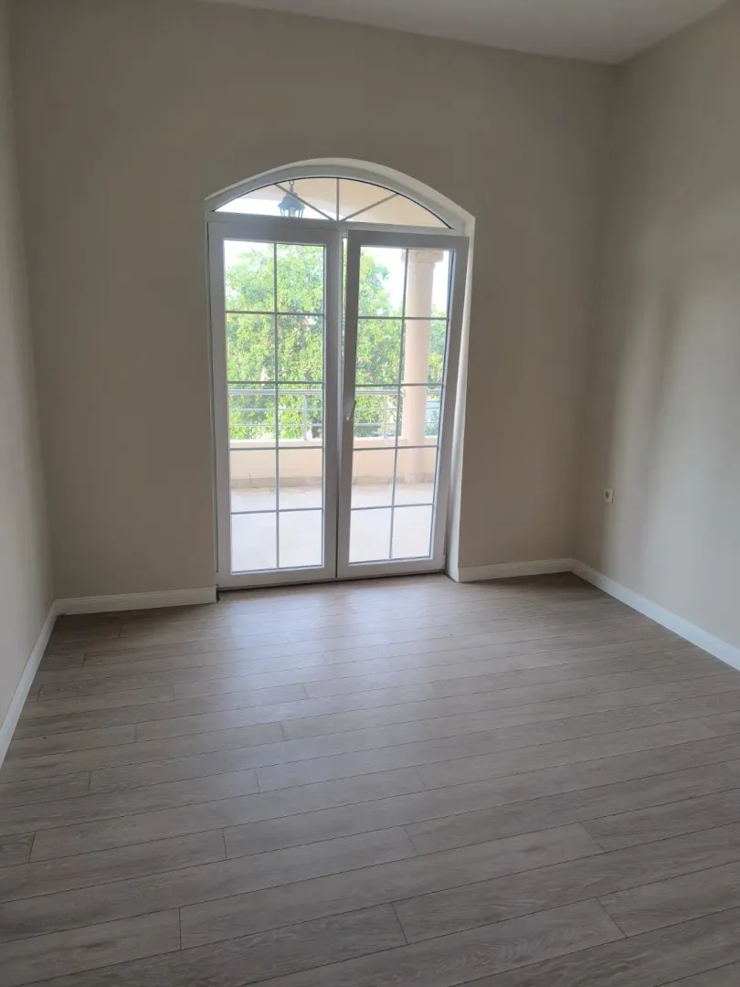 Empty room with laminate flooring and balcony doors.