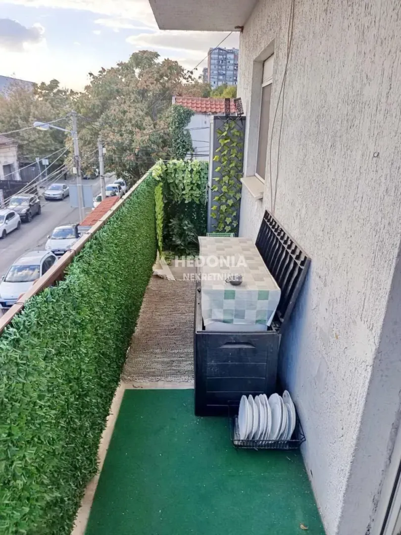 Long balcony with artificial turf and a green-covered fence.