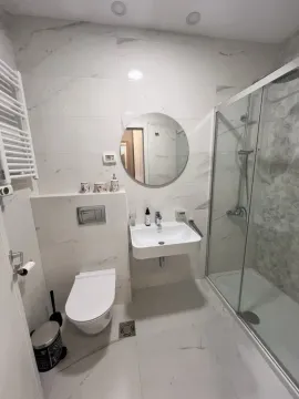 Modernly equipped bathroom with a walk-in shower and white marble tiles. - image 6