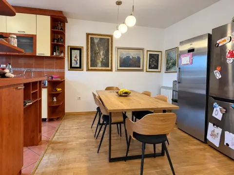 Trpezarija sa drvenim stolom i stolicama, povezana sa kuhinjom. - image 3