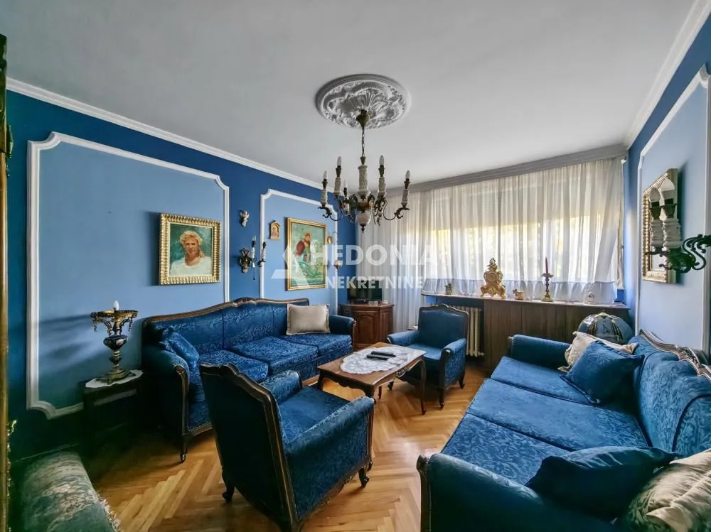 Dnevna soba sa plavim garniturama i klasičnim nameštajem.