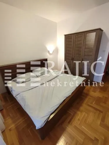 Bedroom with a double bed, wooden wardrobe, and parquet flooring.