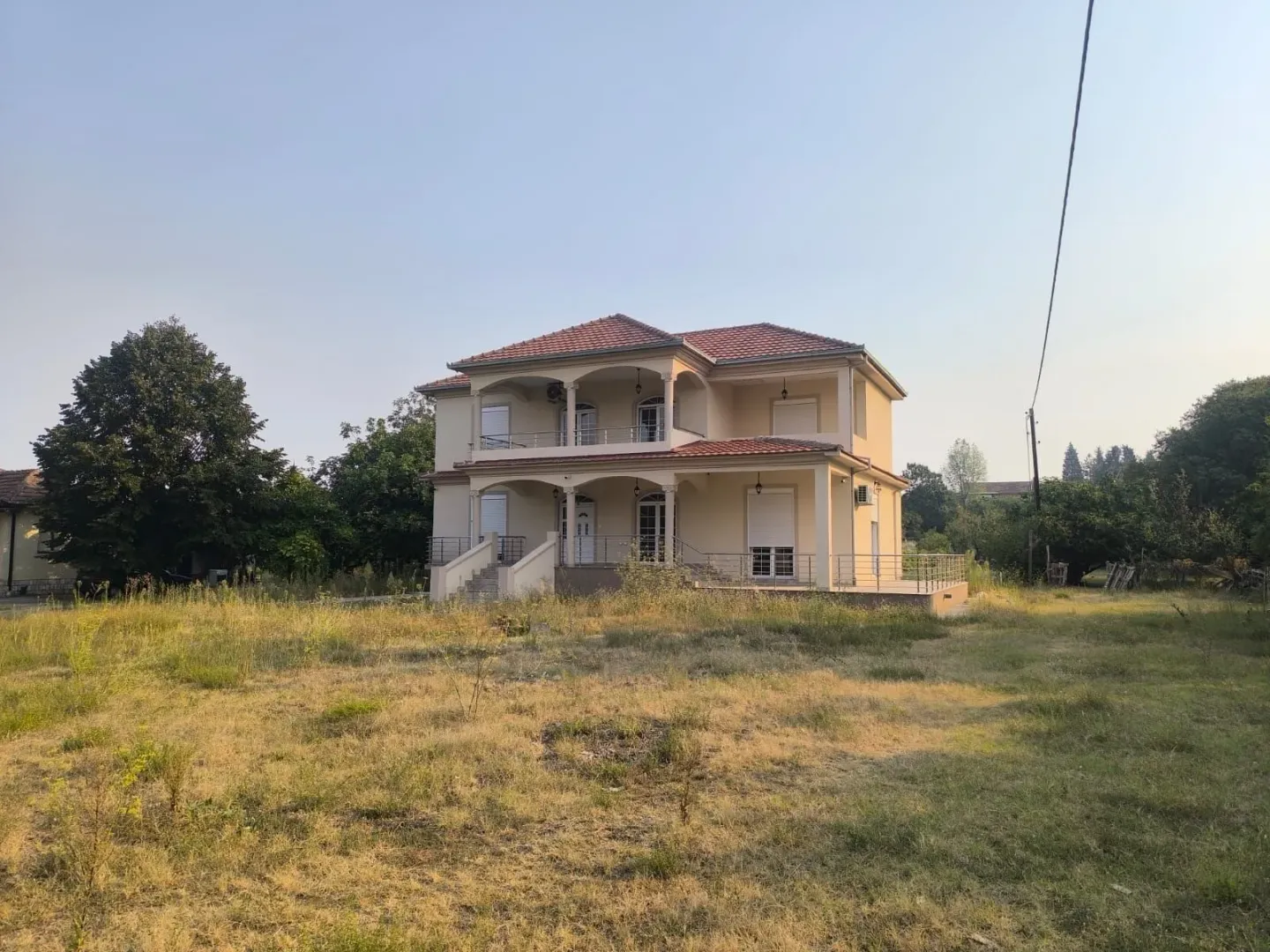 Exterior of a two-story house with terraces and a large yard.