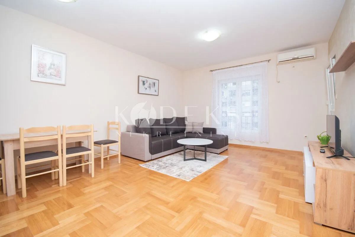 Living room with a sofa, dining table, and TV unit.