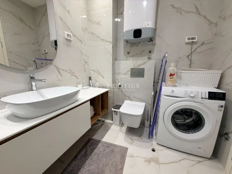Moderne kupatilo sa umivaonikom, WC šoljom, veš mašinom i bojlerom.