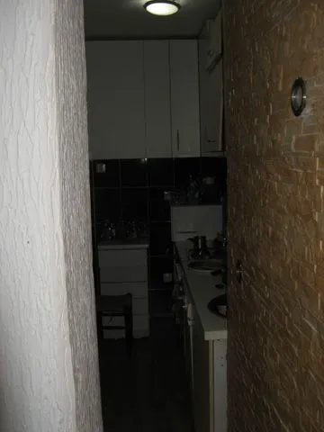 A narrow view of a dark kitchen.