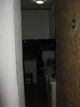 A narrow view of a dark kitchen. - image 6