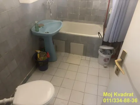 Bathroom equipped with a bathtub, washbasin, and toilet with tiled walls. - image 7