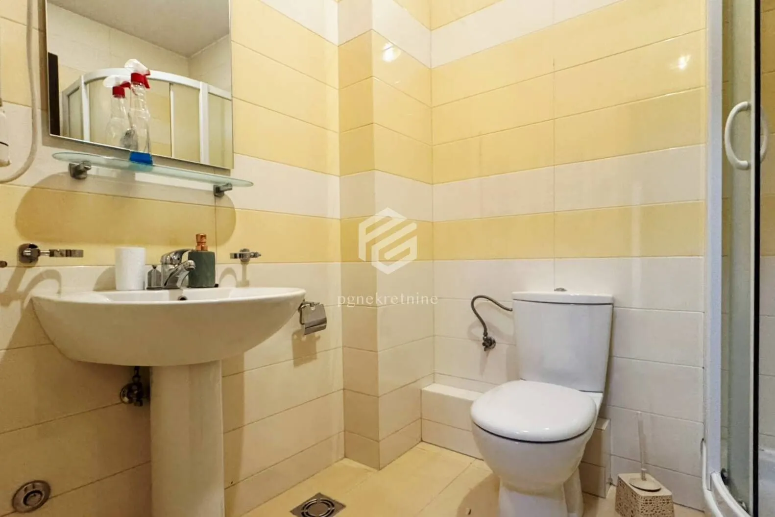 Bathroom tiled in yellow and white with a washbasin and toilet.