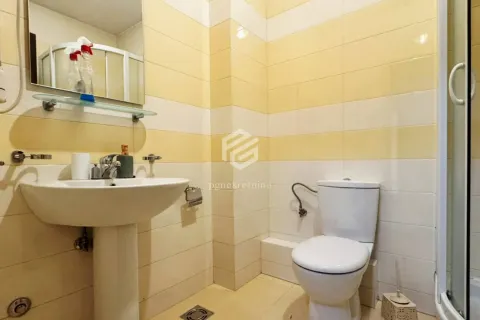 Bathroom tiled in yellow and white with a washbasin and toilet. - image 7