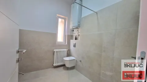 Kupatilo obloženo keramičkim pločicama sa toaletom i radijatorom. - image 6