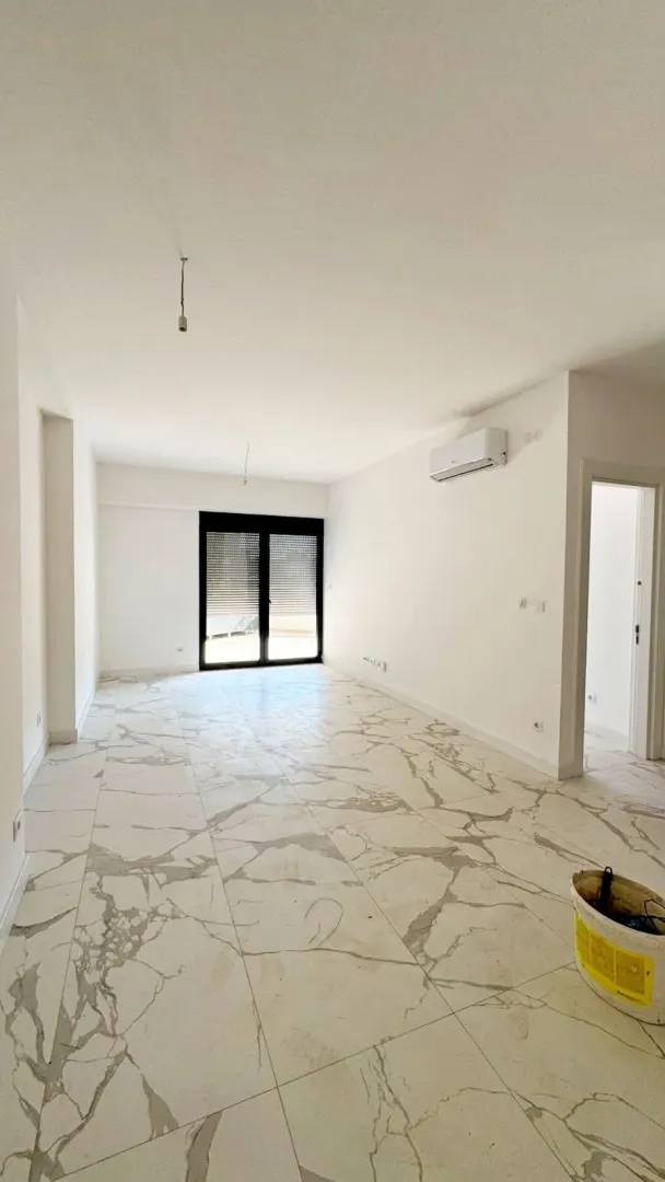 Empty bright room with marble floor tiles and an air conditioner.