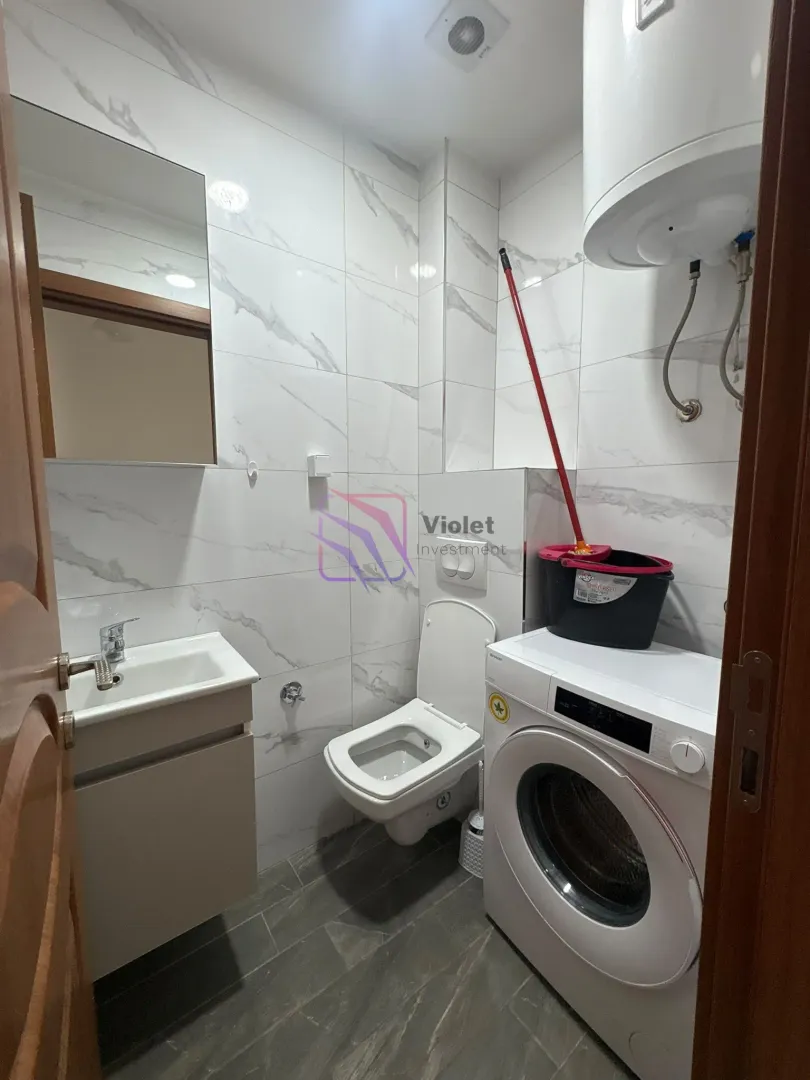 Kupatilo sa veš mašinom, umivaonikom i wc šoljom obloženo mermernim pločicama.