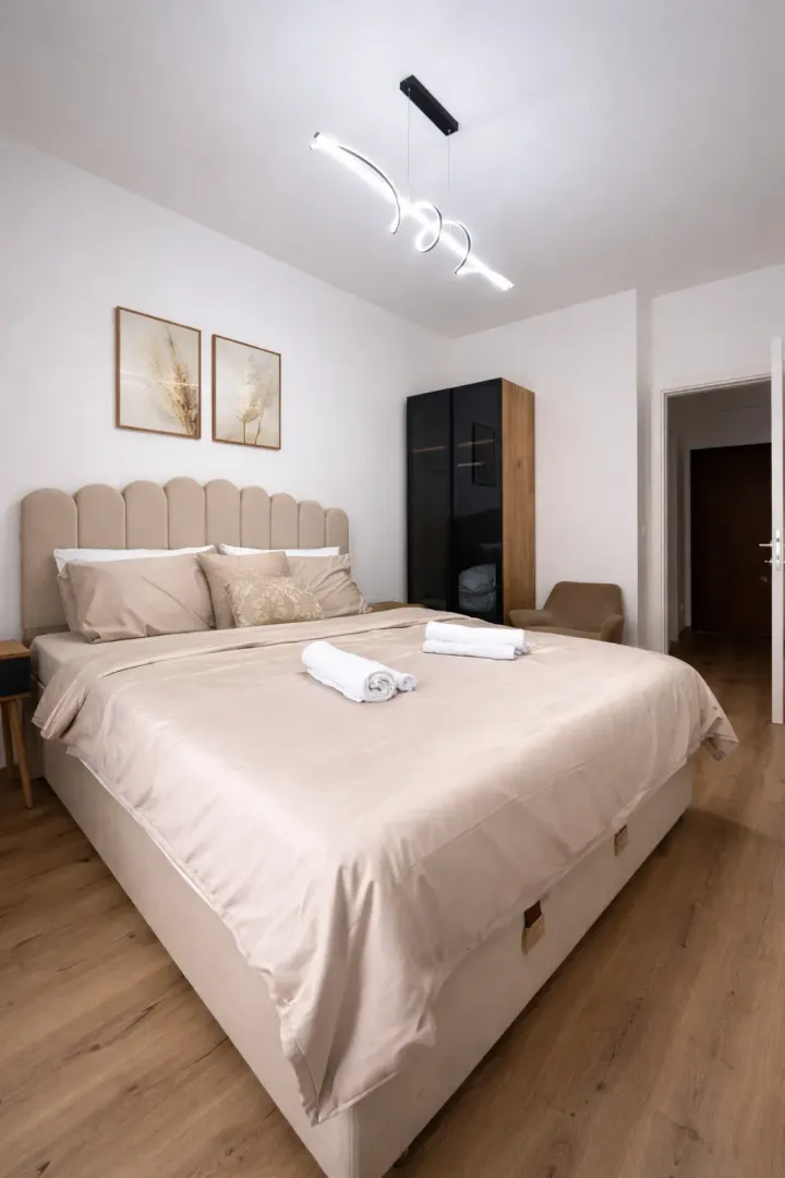 Modern bedroom with a double bed, wardrobe, and wooden flooring.