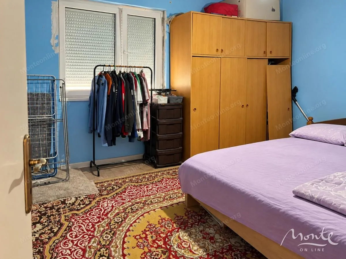 Namještena spavaća soba sa krevetom, ormarom i prozorom.