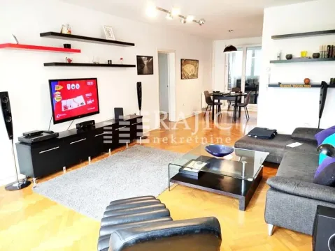 Spacious living room with a sofa, TV, and a dining area in the background. - image 2